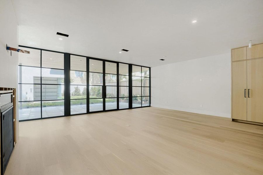 Floor-to-ceiling windows illuminate this expansive living area, offering clear views of the outdoor patio.
