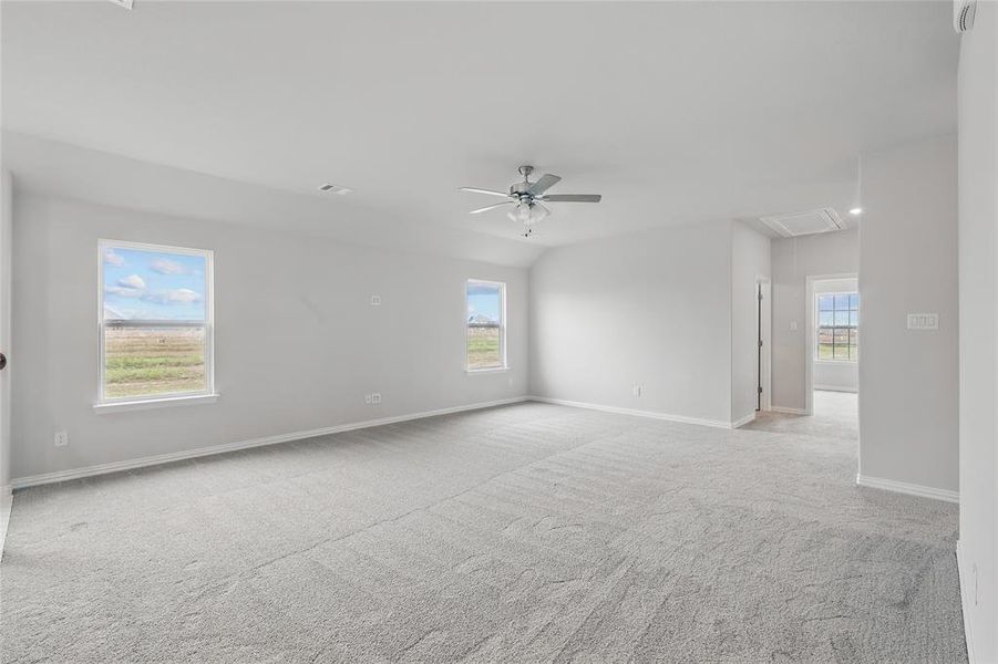 Empty room featuring attic access, light colored carpet, and ceiling fan