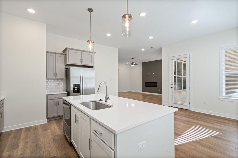 Kitchen featuring stainless steel appliances, gray cabinets, an island with sink, and dark wood finished floors