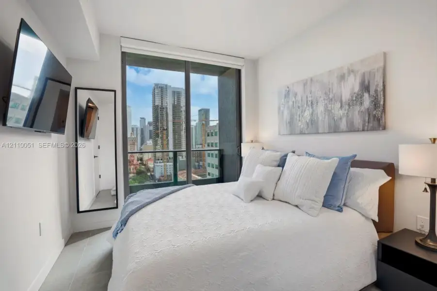 Floor-to-ceiling glass sliding door, Juliet balcony with metal railing, and large-format tile flooring