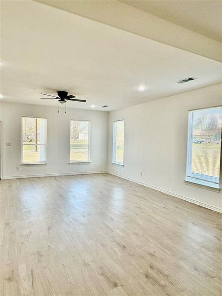 Empty room with light wood finished floors, plenty of natural light, recessed lighting, and ceiling fan