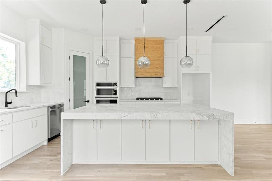 Kitchen featuring sink, a center island, tasteful backsplash, and light hardwood / wood-style flooring