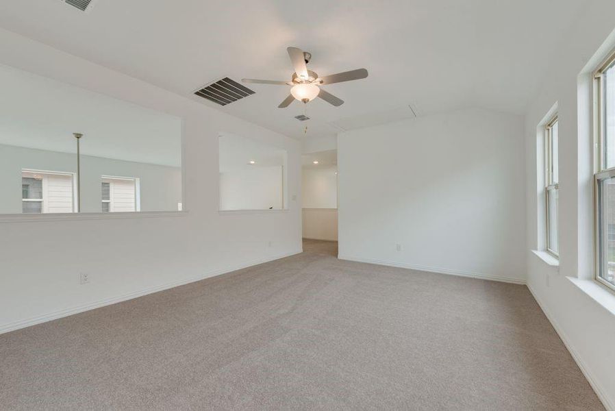 Unfurnished room featuring light colored carpet, healthy amount of natural light, ceiling fan, and lofted ceiling Unfurnished room featuring light colored carpet, healthy amount of natural light, ceiling fan, and lofted ceiling