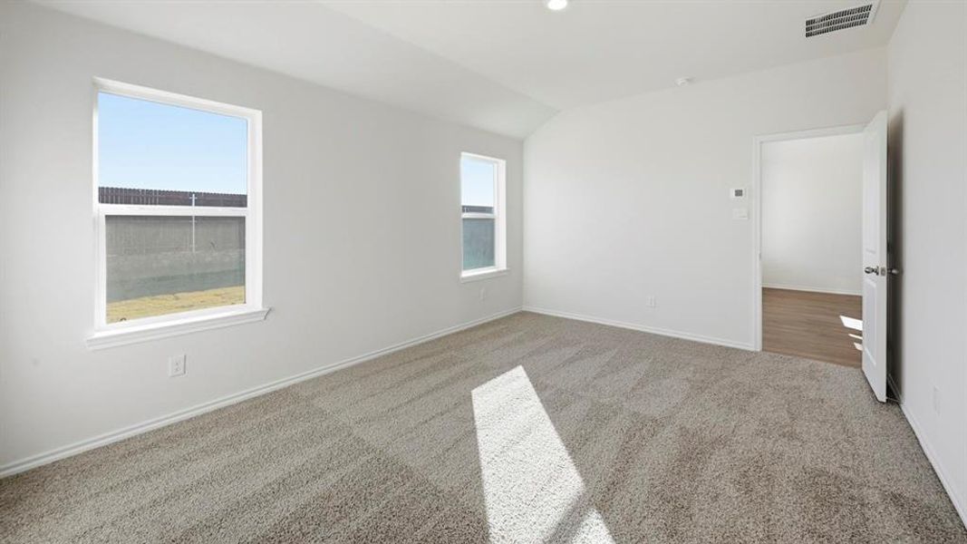Carpeted empty room with vaulted ceiling and baseboards Carpeted empty room with vaulted ceiling and baseboards