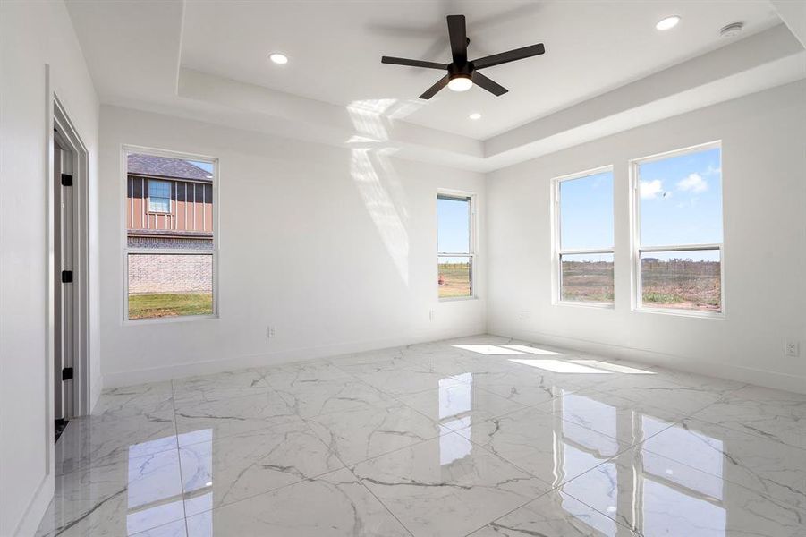 Empty room with ceiling fan and a tray ceiling