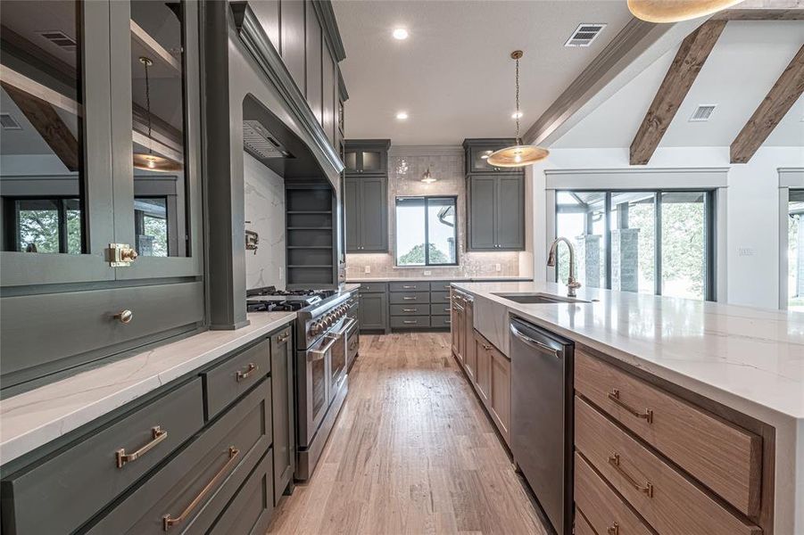 Kitchen with light stone counters, beamed ceiling, stainless steel appliances, light wood finished floors, and recessed lighting Kitchen with light stone counters, beamed ceiling, stainless steel appliances, light wood finished floors, and recessed lighting