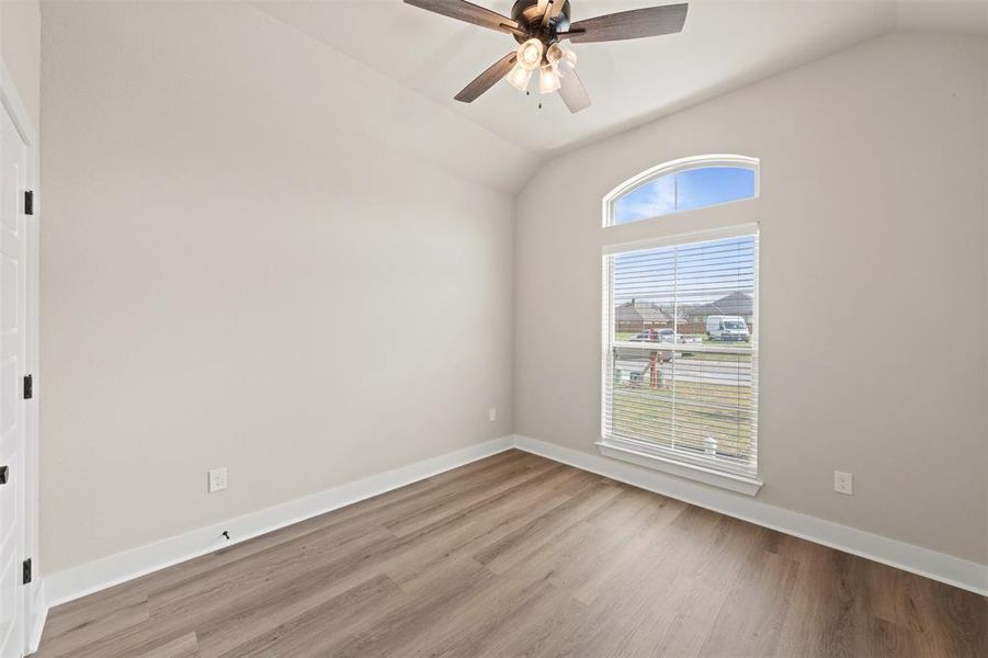 Empty room with lofted ceiling, light wood-style floors, and ceiling fan