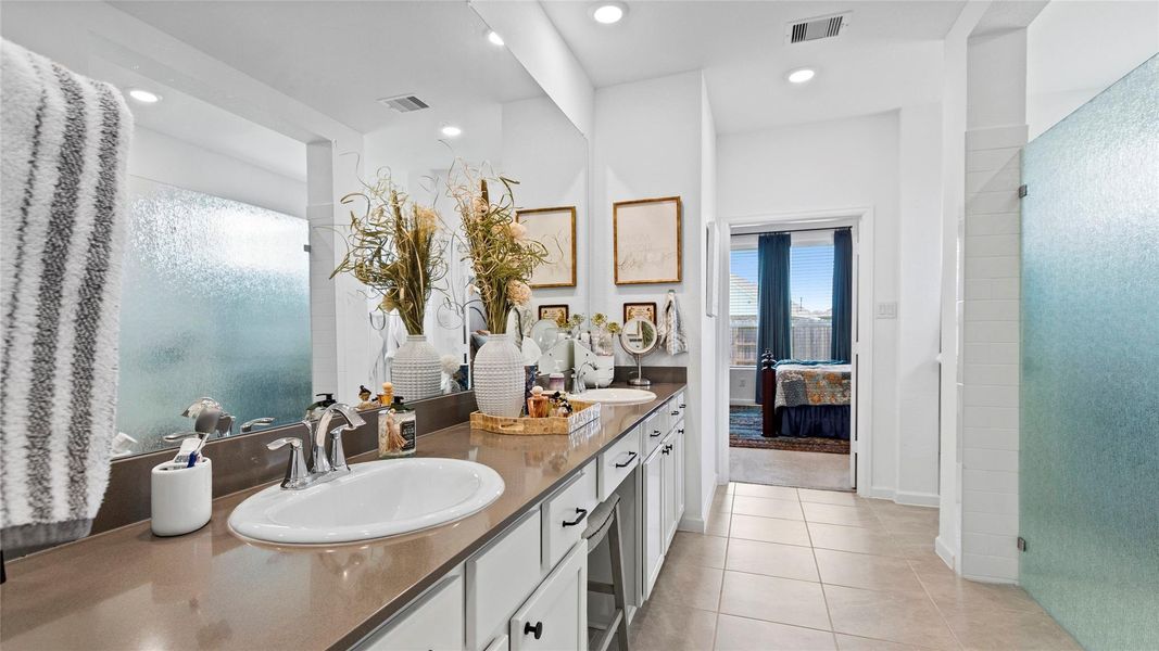 Spacious bathroom featuring a dual-sink vanity, elegant fixtures, and ample natural light, seamlessly connected to the bedroom through a doorway with a view. Spacious bathroom featuring a dual-sink vanity, elegant fixtures, and ample natural light, seamlessly connected to the bedroom through a doorway with a view.
