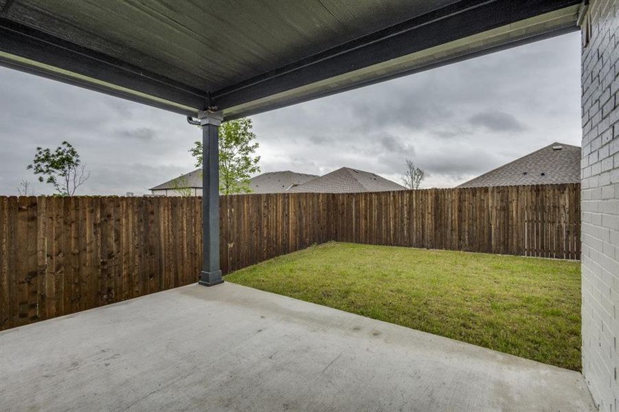 Covered patio with concrete flooring, supported by a substantial column