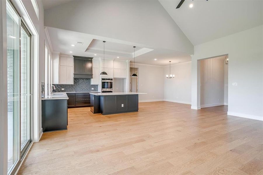 Kitchen with oven, light hardwood / wood-style flooring, a kitchen island, and hanging light fixtures