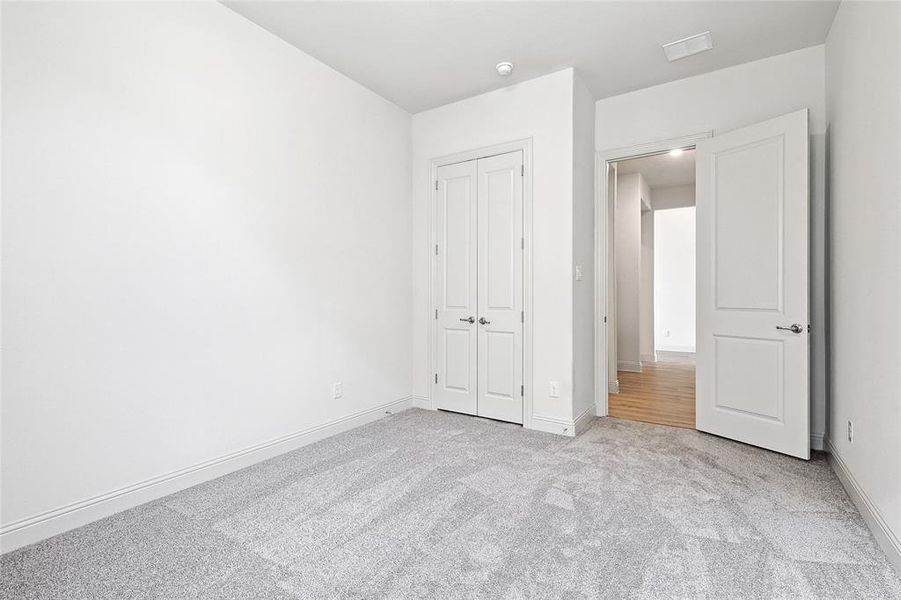 Unfurnished bedroom with light carpet and a closet