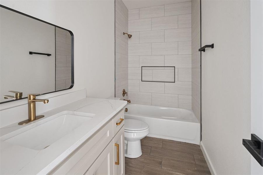 Bathroom featuring a rectangular undermount sink, a white countertop, gold-finish fixtures, and wood-finish flooring