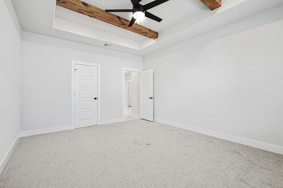 Empty room with beamed ceiling, ceiling fan, and carpet