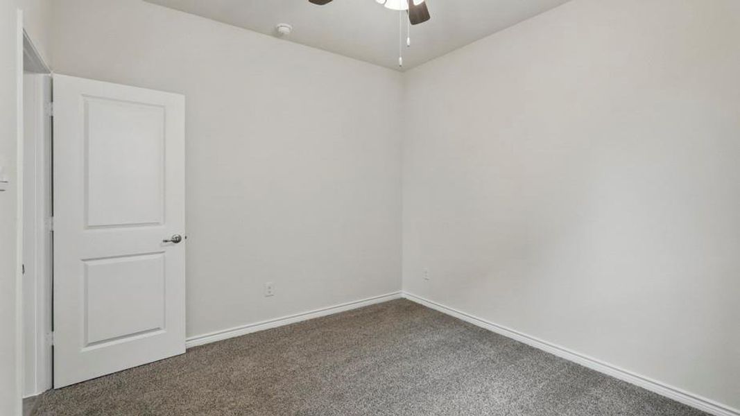 Unfurnished room featuring dark carpet and a ceiling fan