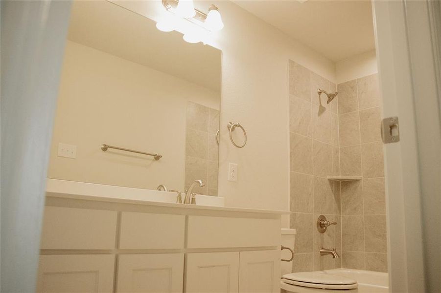 Full bathroom with vanity, toilet, and tiled shower / bath combo