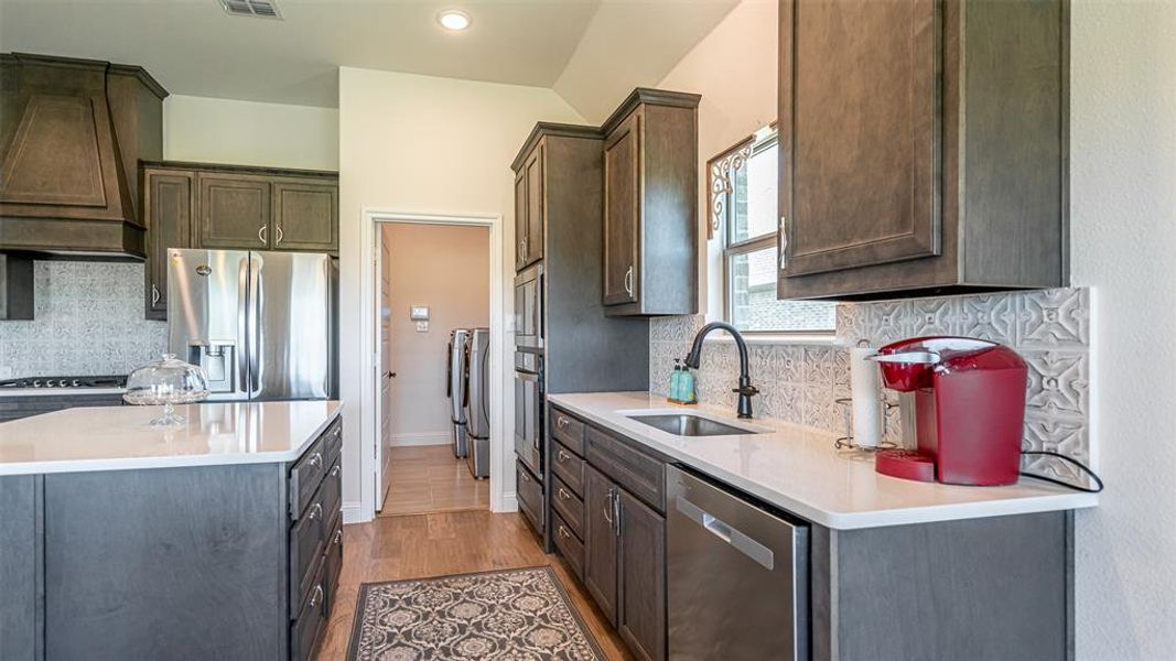 Kitchen featuring dark wood-finish cabinetry, stainless steel appliances, white countertops, and a patterned tile backsplash