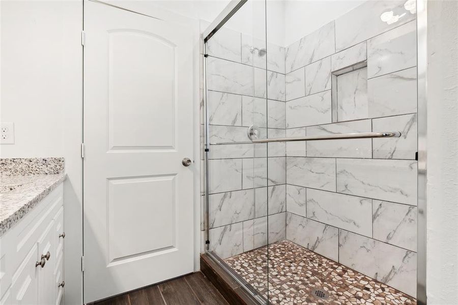 Bathroom featuring walk in shower, hardwood / wood-style flooring, and vanity