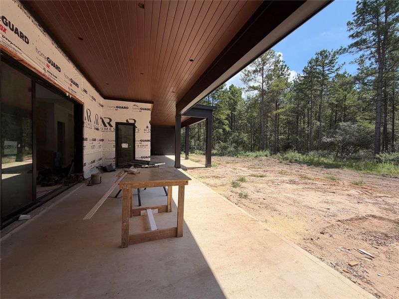 Expanded outdoor covered patio with outdoor kitchen and view of the wooded acreage Expanded outdoor covered patio with outdoor kitchen and view of the wooded acreage