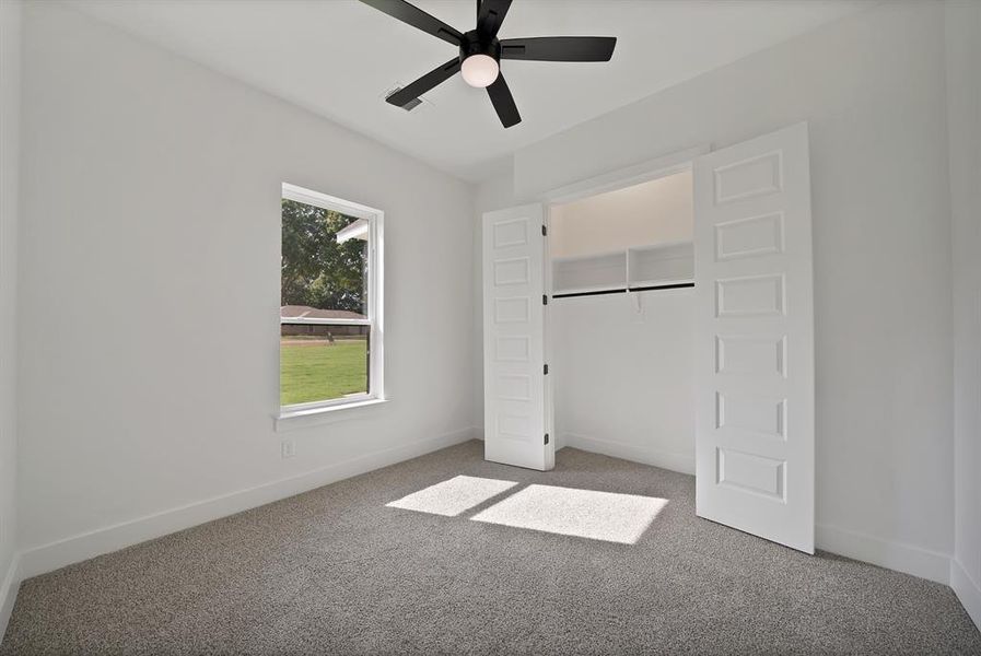 Unfurnished bedroom featuring carpet flooring and a ceiling fan Unfurnished bedroom featuring carpet flooring and a ceiling fan
