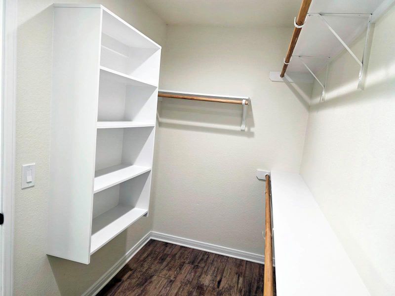 Walk in closet with dark wood-style flooring