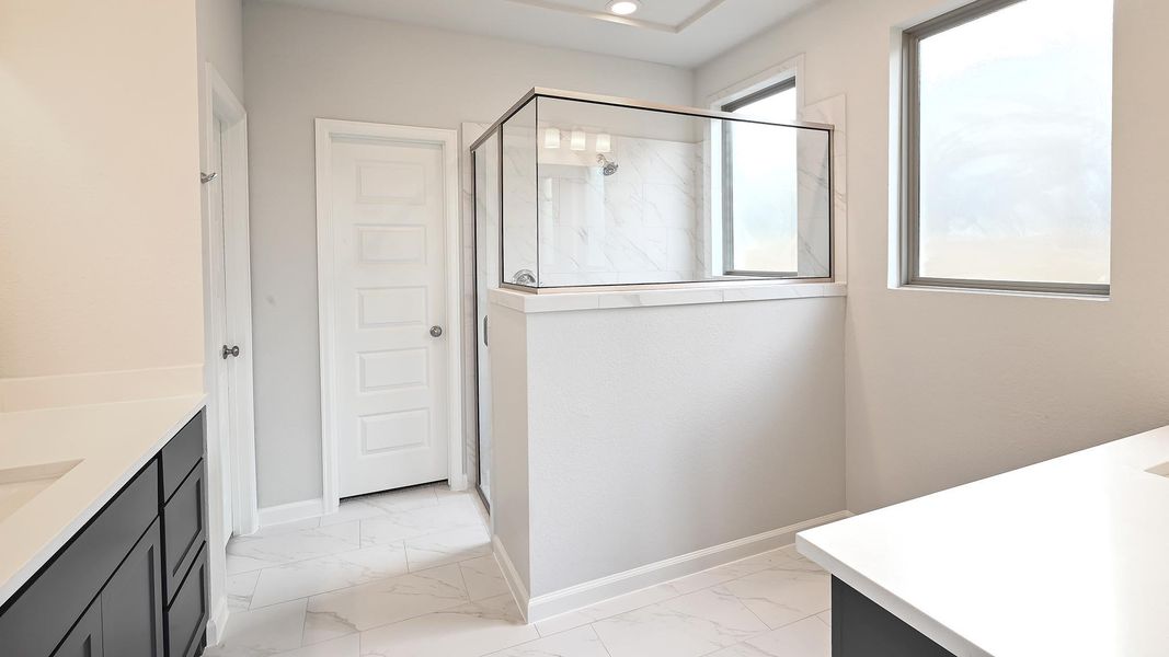Bathroom featuring vanity, light marble finish flooring, and a marble finish shower Bathroom featuring vanity, light marble finish flooring, and a marble finish shower