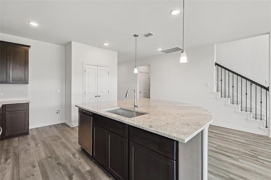 Kitchen featuring a center island with sink, pendant lighting, light hardwood / wood-style floors, and sink