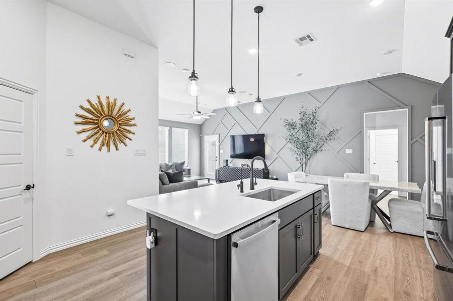 Kitchen with an accent wall, pendant lighting, a kitchen island with sink, open floor plan, and stainless steel appliances