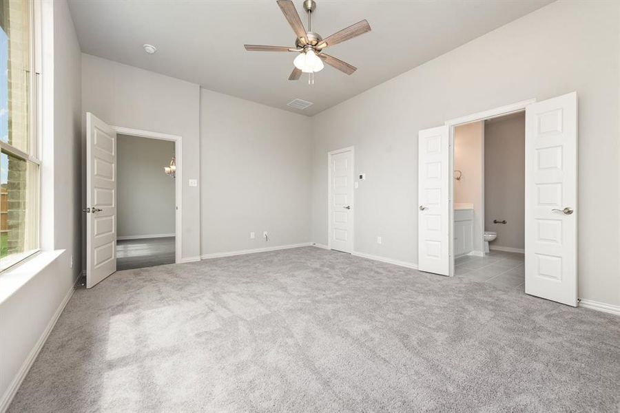 Unfurnished bedroom with ensuite bathroom, light colored carpet, and ceiling fan