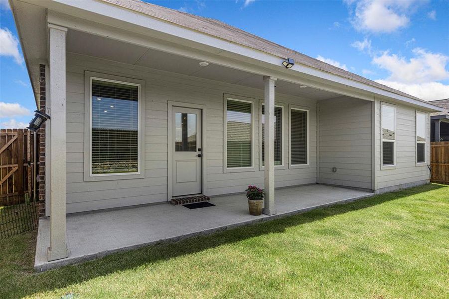 Covered patio extending across the rear facade, featuring multiple large windows, a glass-paneled door, and durable siding Covered patio extending across the rear facade, featuring multiple large windows, a glass-paneled door, and durable siding