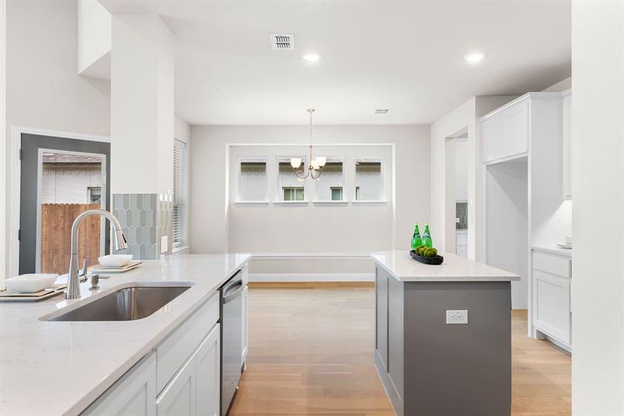 Kitchen with a center island, sink, light hardwood / wood-style flooring, and decorative light fixtures