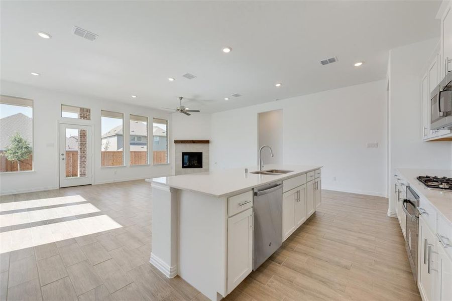 Kitchen featuring sink, white cabinetry, a center island with sink, and stainless steel appliances