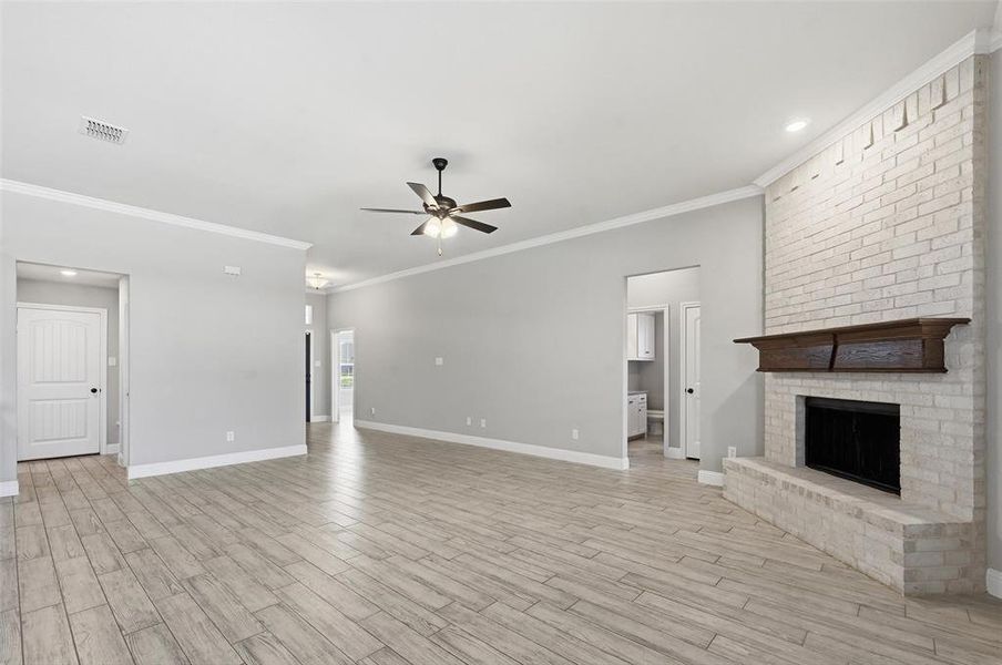 Unfurnished living room with a fireplace, ceiling fan, recessed lighting, wood finish floors, and ornamental molding Unfurnished living room with a fireplace, ceiling fan, recessed lighting, wood finish floors, and ornamental molding