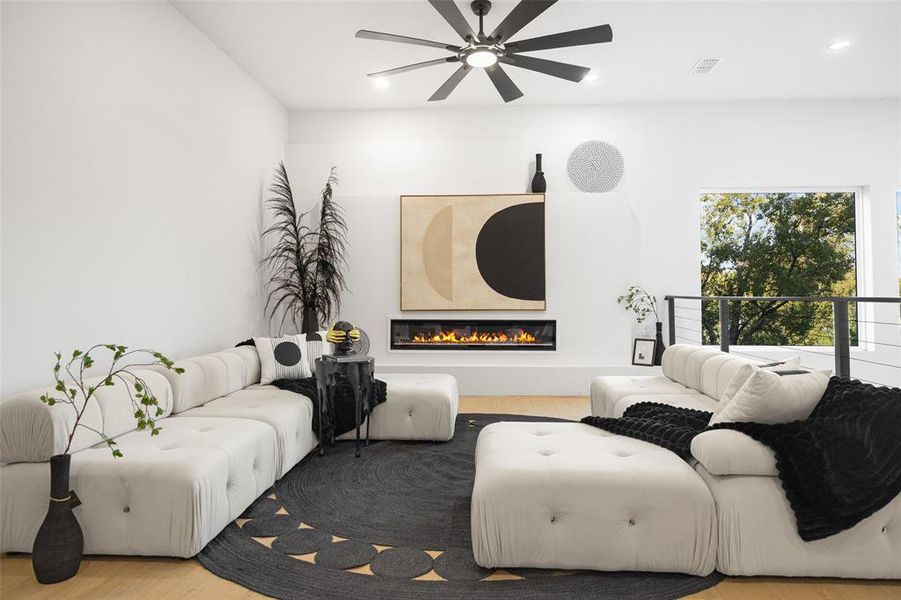 Living room featuring wood finished floors, a glass covered fireplace, and recessed lighting