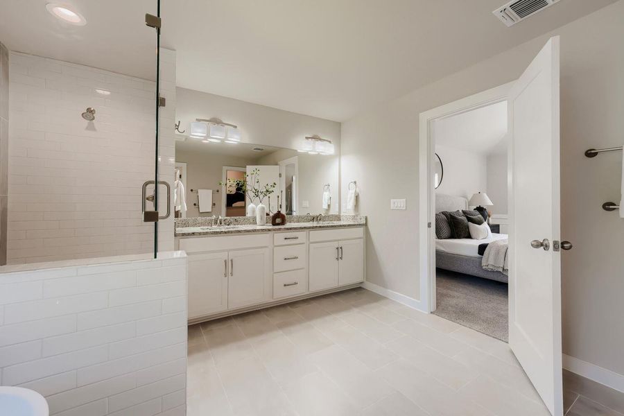 A well-lit primary bathroom features a double vanity and a spacious walk-in shower. A well-lit primary bathroom features a double vanity and a spacious walk-in shower.