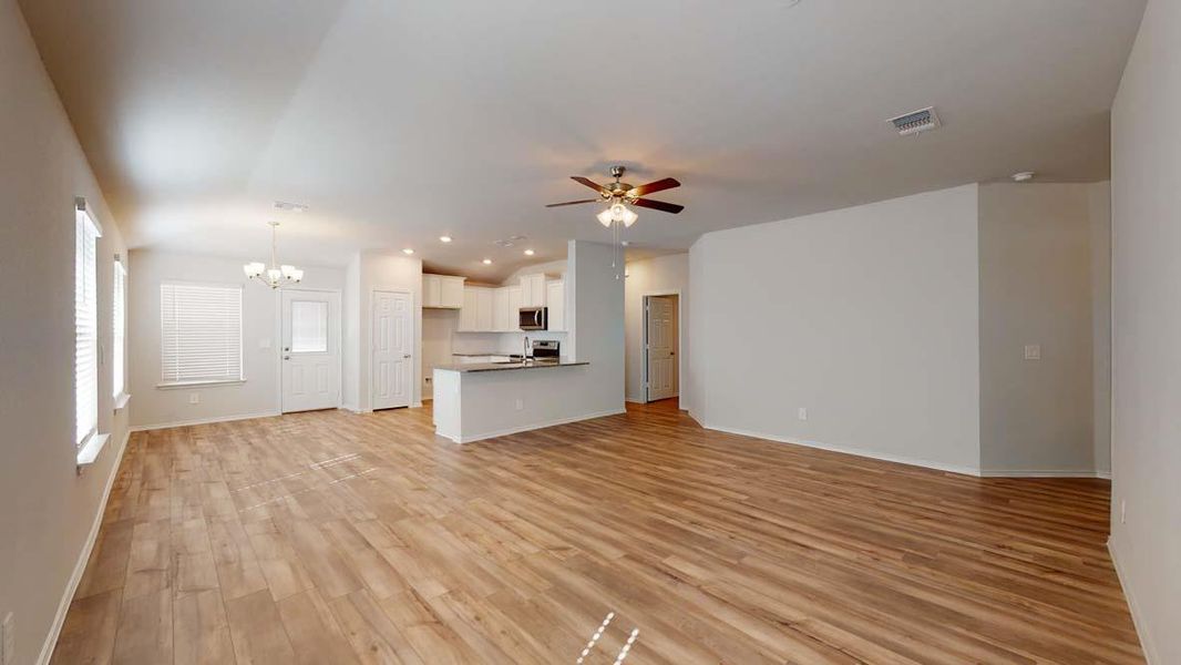 Unfurnished living room featuring suspended lighting, light wood-type flooring, a ceiling fan, and vaulted ceiling