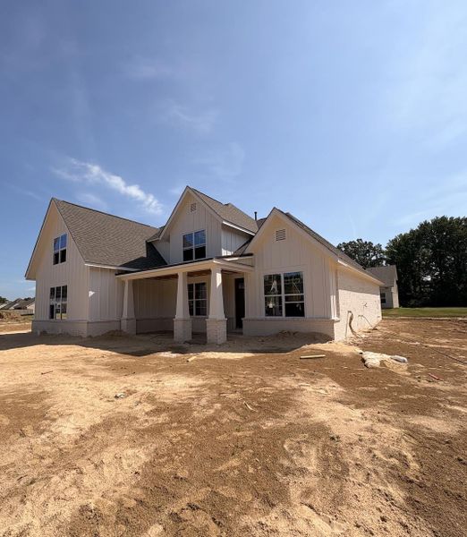 Modern farmhouse-style residence with a covered porch, board and batten siding, brick skirting, and multiple gables Modern farmhouse-style residence with a covered porch, board and batten siding, brick skirting, and multiple gables