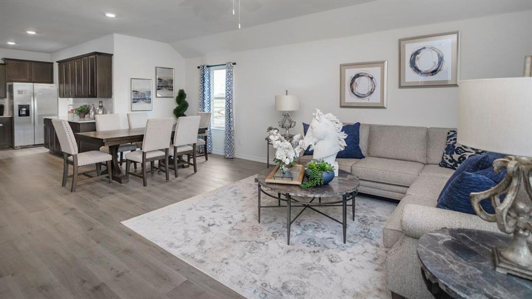 Open-concept living area featuring wood-finish flooring, recessed lighting, and vaulted ceilings