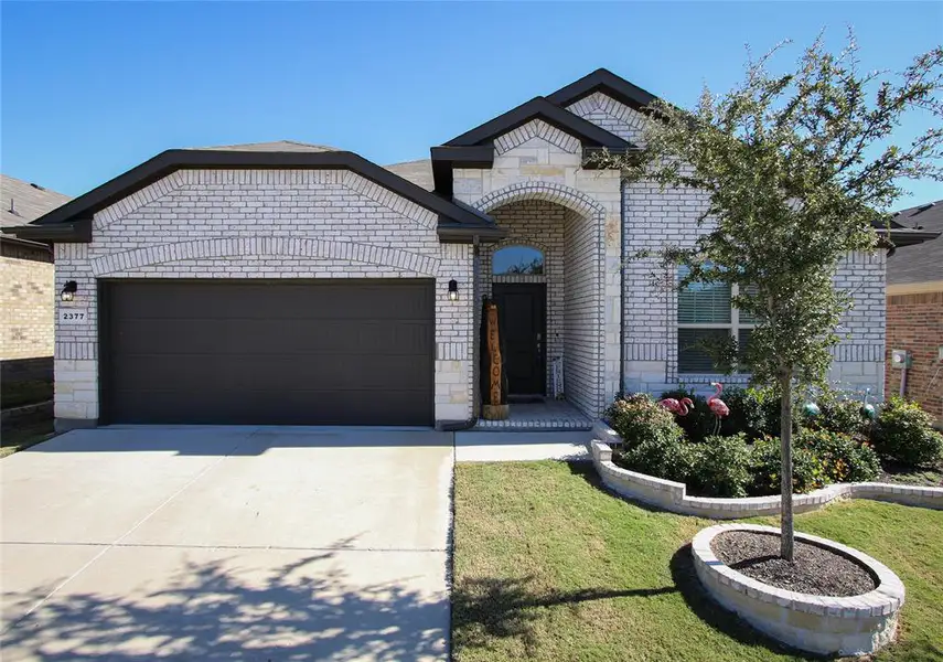 Welcome to 2377 Waggoner Ranch Drive in Weatherford, a modern single-story brick home features a spacious two-car garage, an inviting front entryway with elegant landscaping, and a manicured lawn for excellent curb appeal.