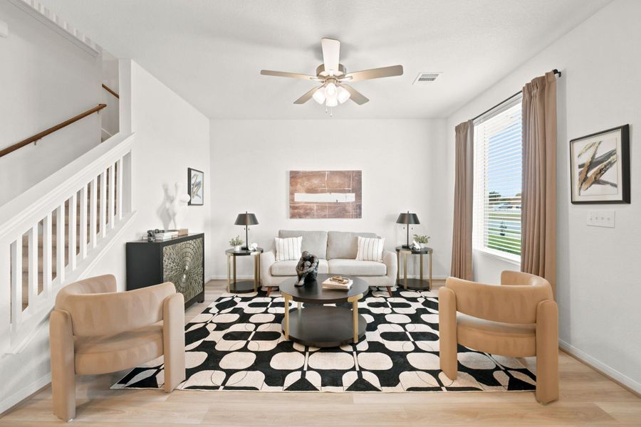 Clean lines and warm wood floors define this bright living room adjacent to the stairs.