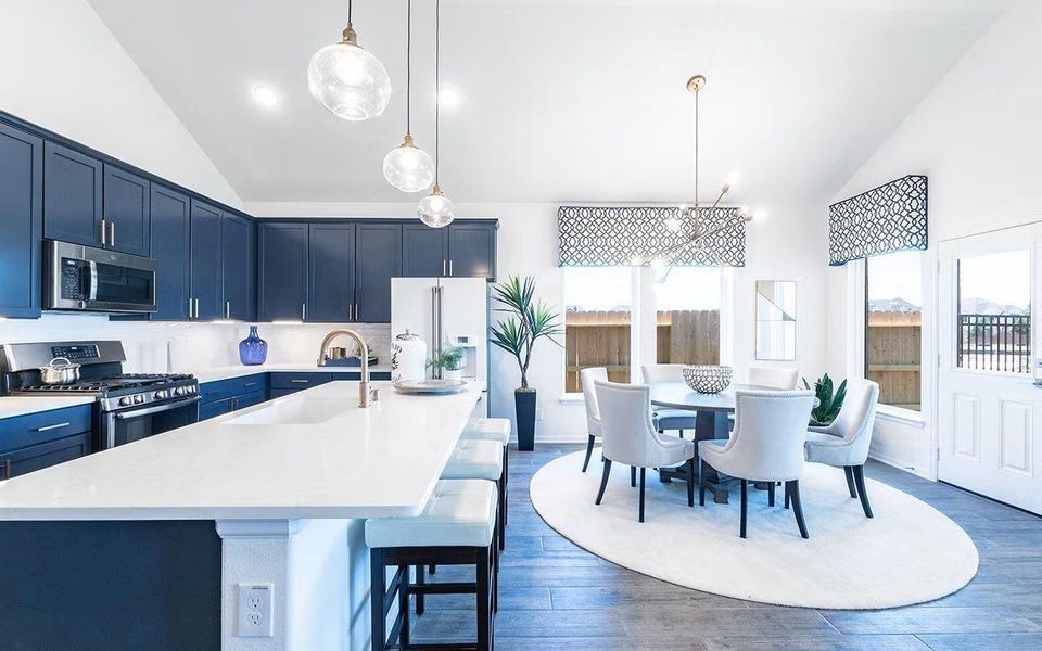 Open concept kitchen and dining area designed for connection and convenience, highlighted by a large center island, breakfast bar seating, granite countertops, and woodlike vinyl plank flooring that carries through the main living spaces, creating a seamless flow into the family room. **Photos are representative only and may vary as built.** Open concept kitchen and dining area designed for connection and convenience, highlighted by a large center island, breakfast bar seating, granite countertops, and woodlike vinyl plank flooring that carries through the main living spaces, creating a seamless flow into the family room. **Photos are representative only and may vary as built.**