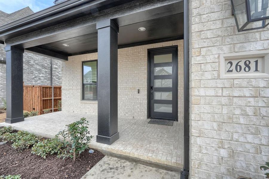 Doorway to property featuring a porch, fence, and brick siding