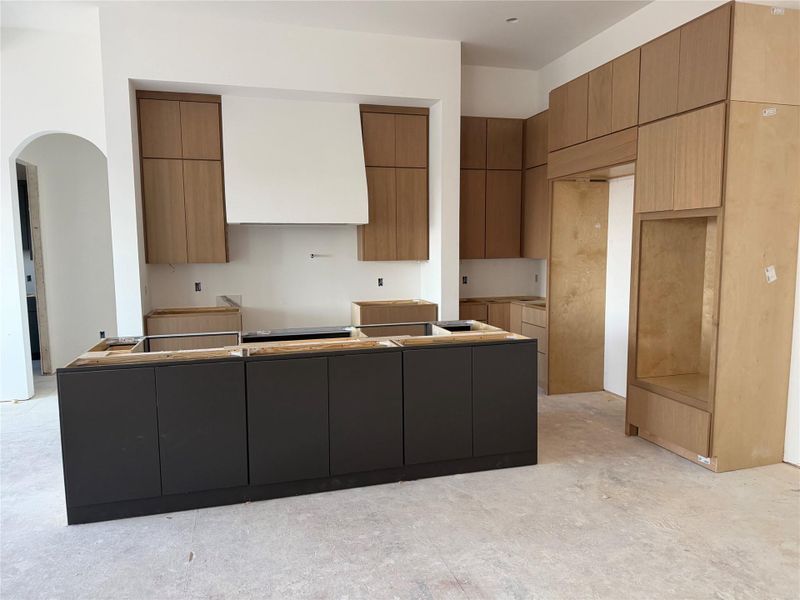 Kitchen featuring a center island, ventilation hood, modern cabinets, arched walkways, and two tone cabinets