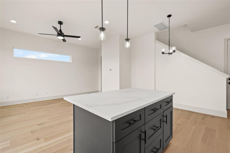 The island — dark base with quartz top and drawer storage on all sides The island — dark base with quartz top and drawer storage on all sides