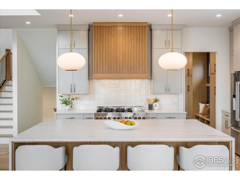 If you love entertaining, you'll be thrilled with this gorgeous Kitchen island, custom vent hood, warm lighting and cascading double waterfall quartz counters