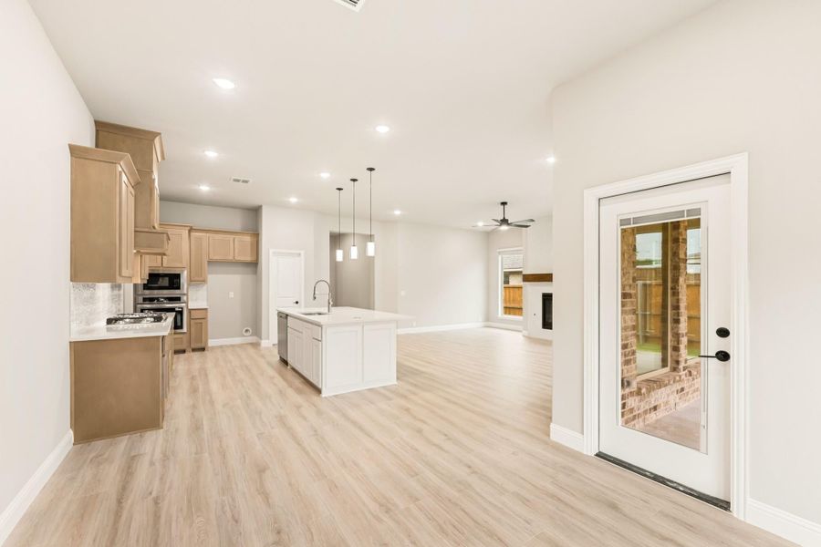 Open-concept kitchen and living area with wood cabinets, center island, and light hardwood floors Open-concept kitchen and living area with wood cabinets, center island, and light hardwood floors