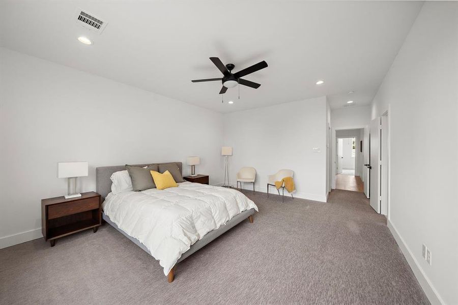 This spacious owner's bedroom is bathed in natural light, creating a bright and serene retreat. Large windows highlight the elegant design, offering a perfect space for relaxation and rest.