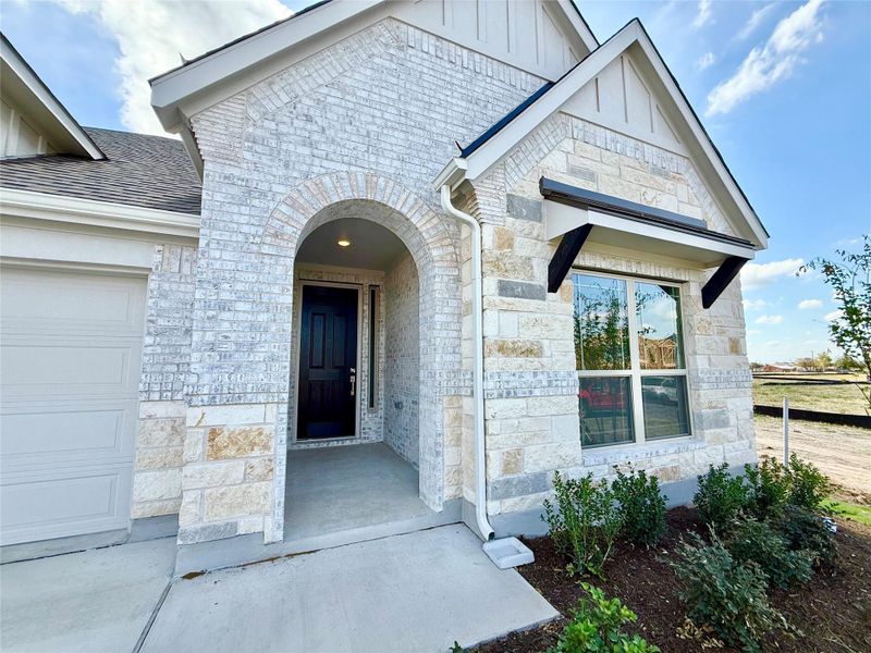 Property entrance featuring stone siding, board and batten siding, and an attached garage