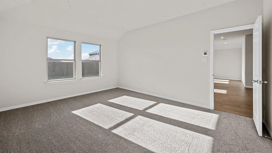 Spare room featuring dark colored carpet and lofted ceiling