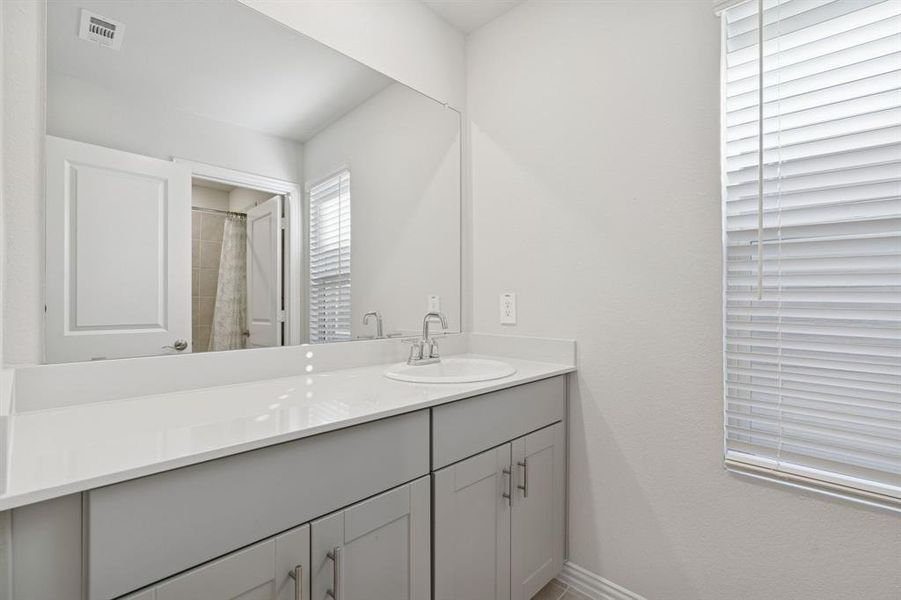 Full bathroom with curtained shower and vanity