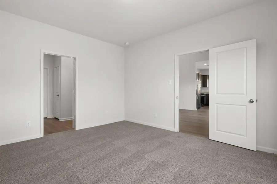 Unfurnished bedroom with carpet and stainless steel fridge with ice dispenser